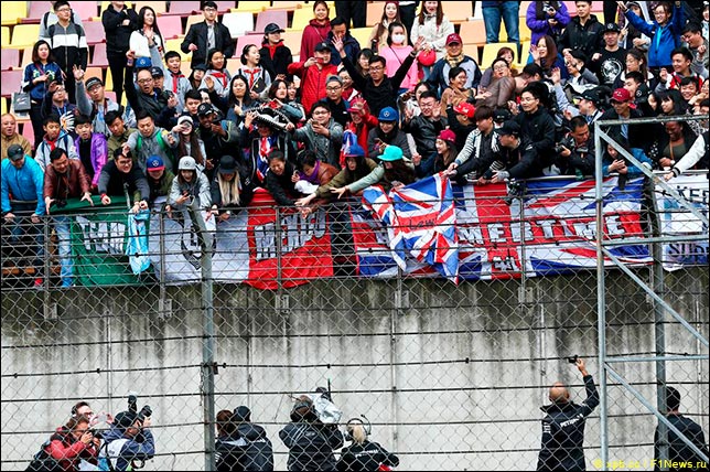 Льюис Хэмилтон подписывает футболки у главной трибуны